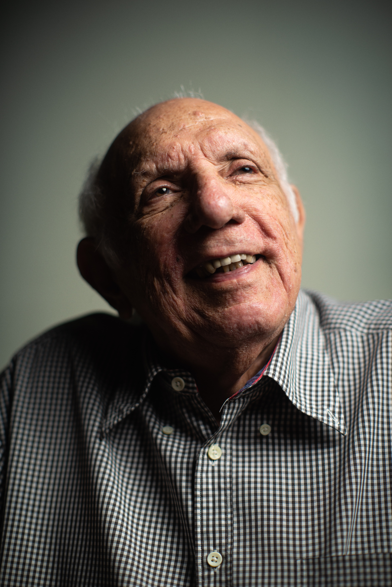 Professor Jorge Miguel sorrindo, retrato em camisa xadrez